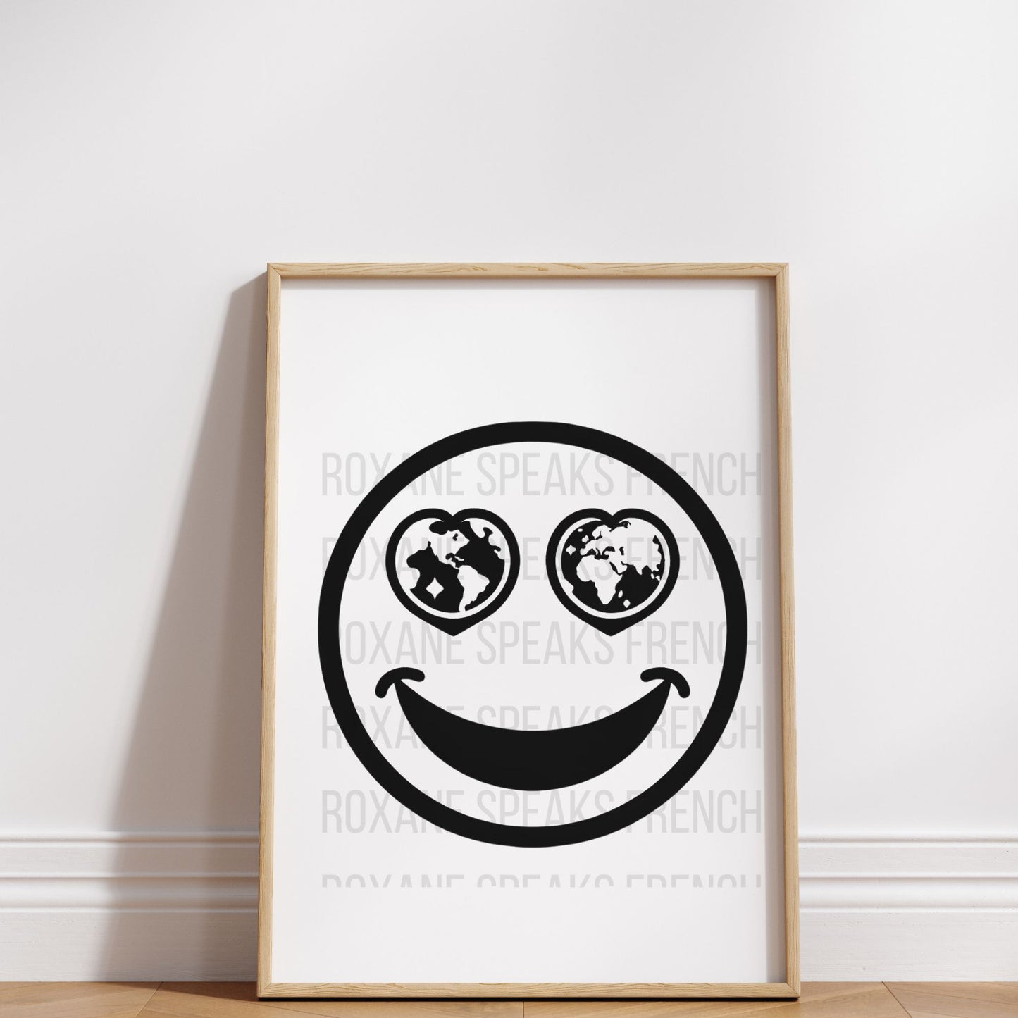 A framed poster on a wall features a smiley face with two globes as eyes and a curved smile, against a white background watermarked with "ROXANE SPEAKS FRENCH".